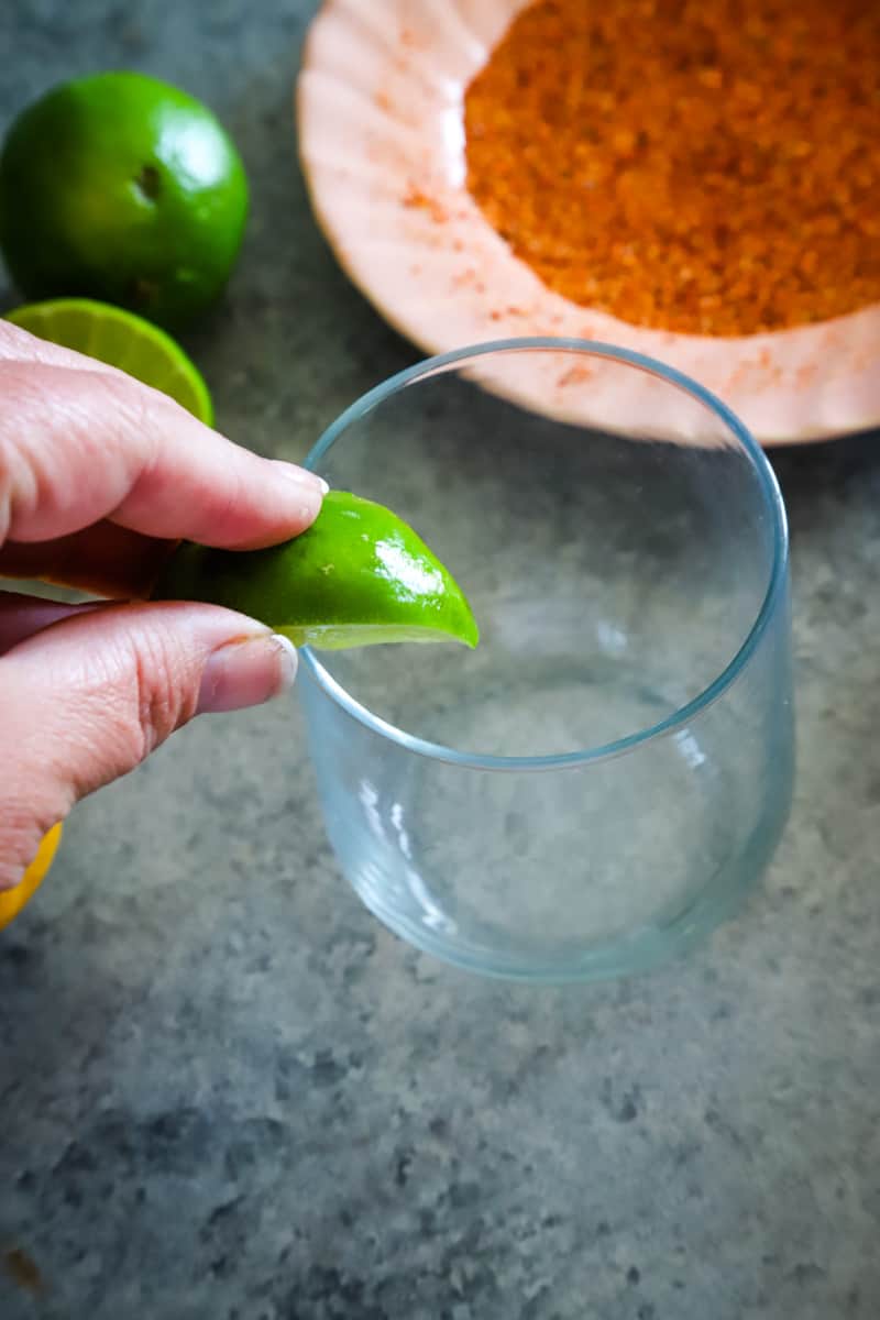 Putting lime juice on the rim of the margarita glass. 