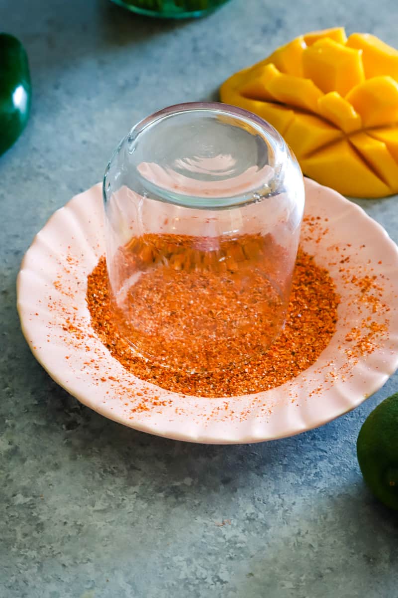 Putting the glass in a small plate with Tajin Seasoning. 