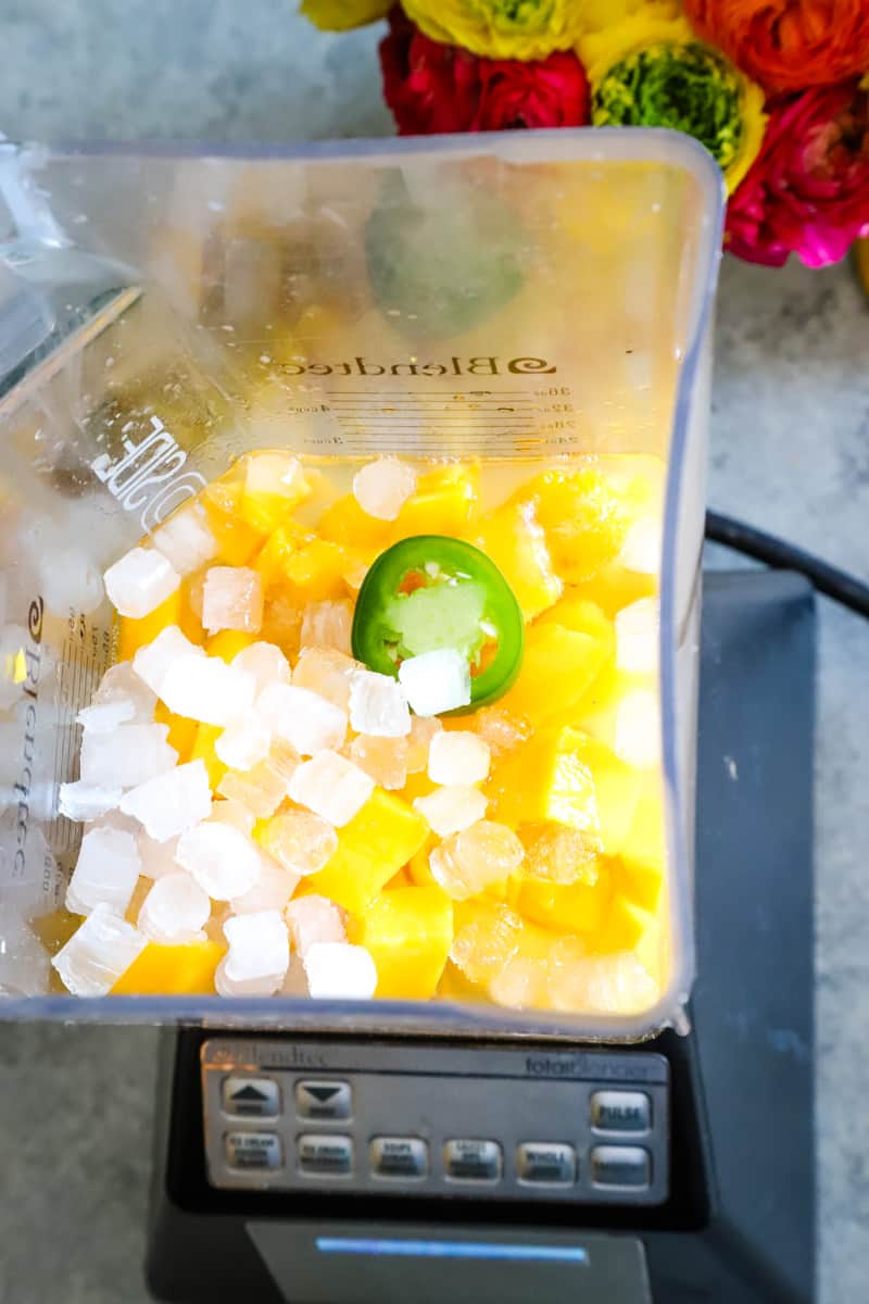 Mango margarita with ice cubes and jalapeño slices. 