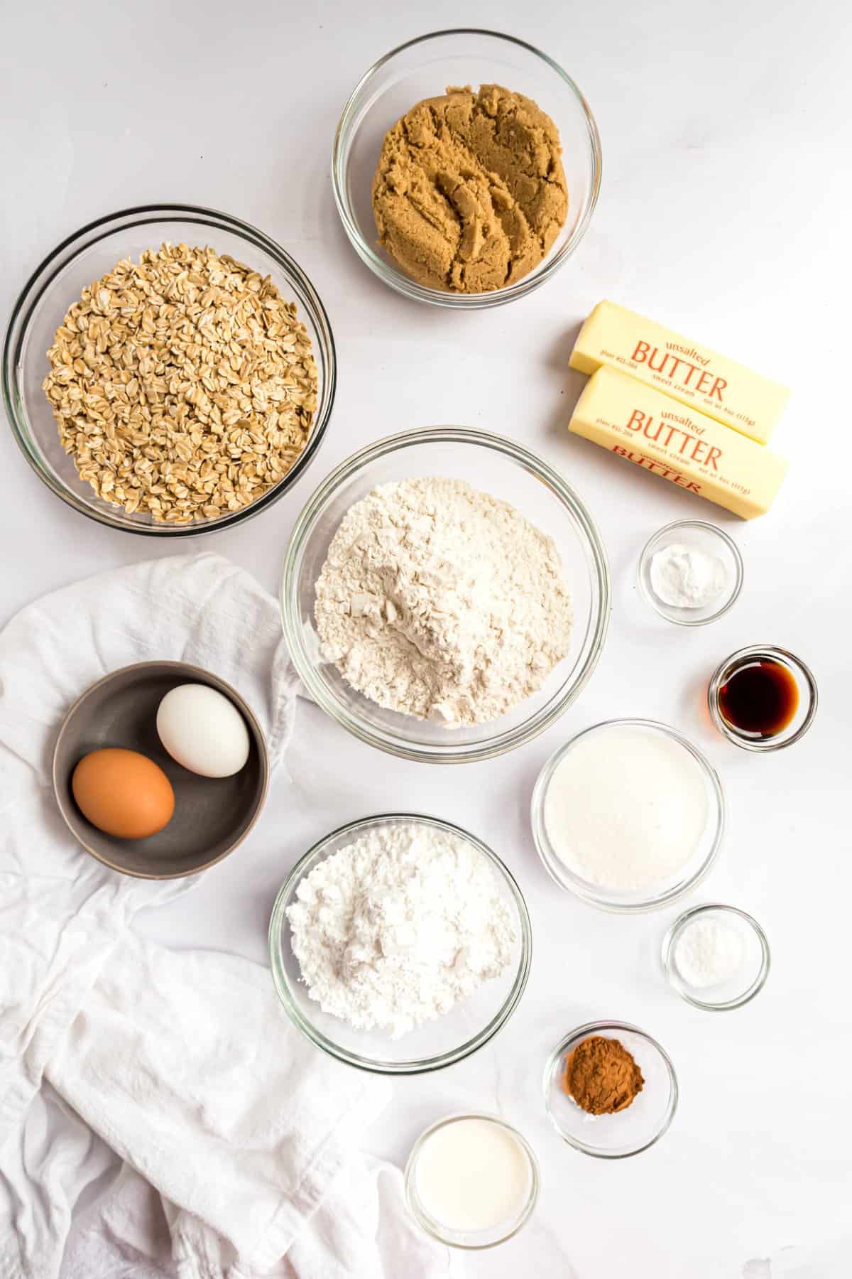 Ingredients to make cookies in small glass bowls on white background. 