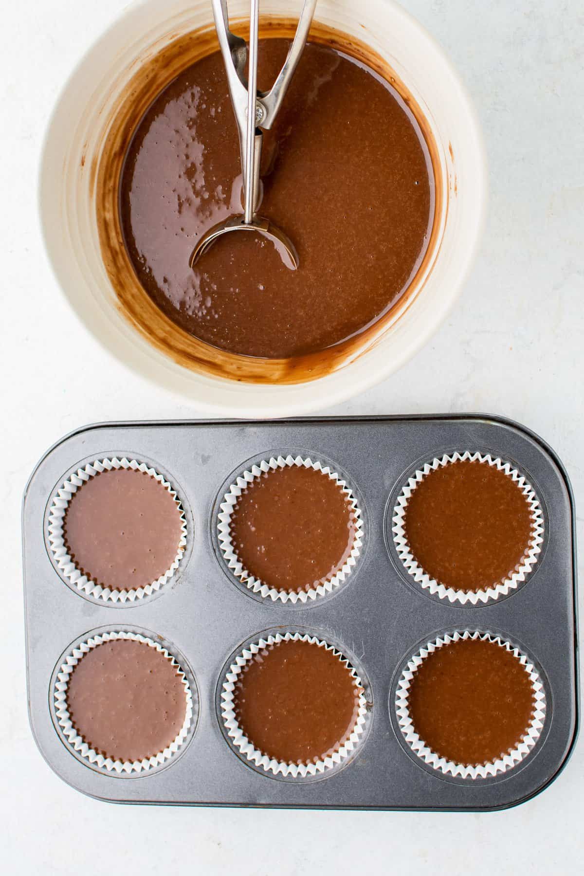 Scooping the chocolate batter into the lined cupcake tin. 