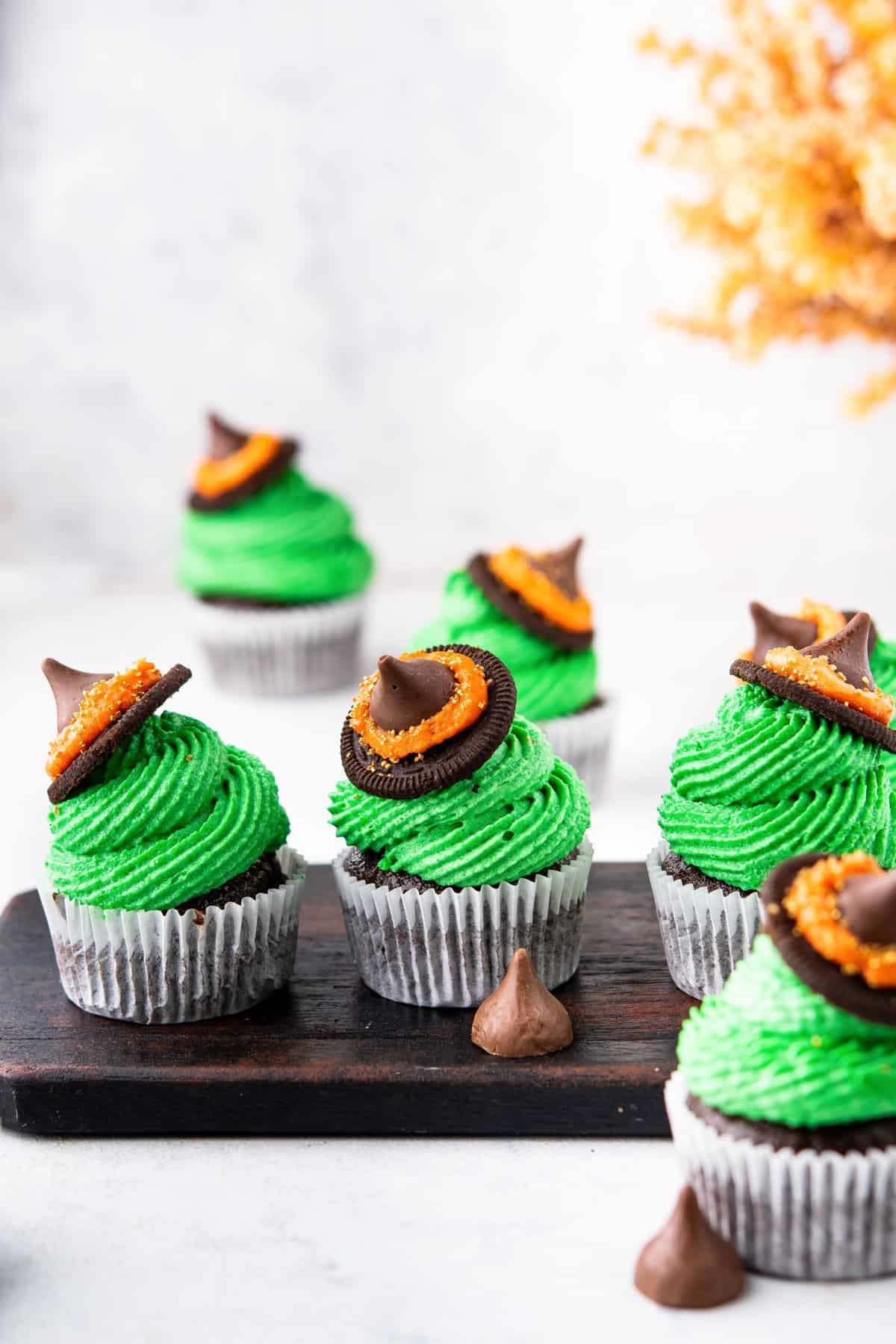 three witch's hat cupcakes on black serving dish with more cupcakes in the background. 