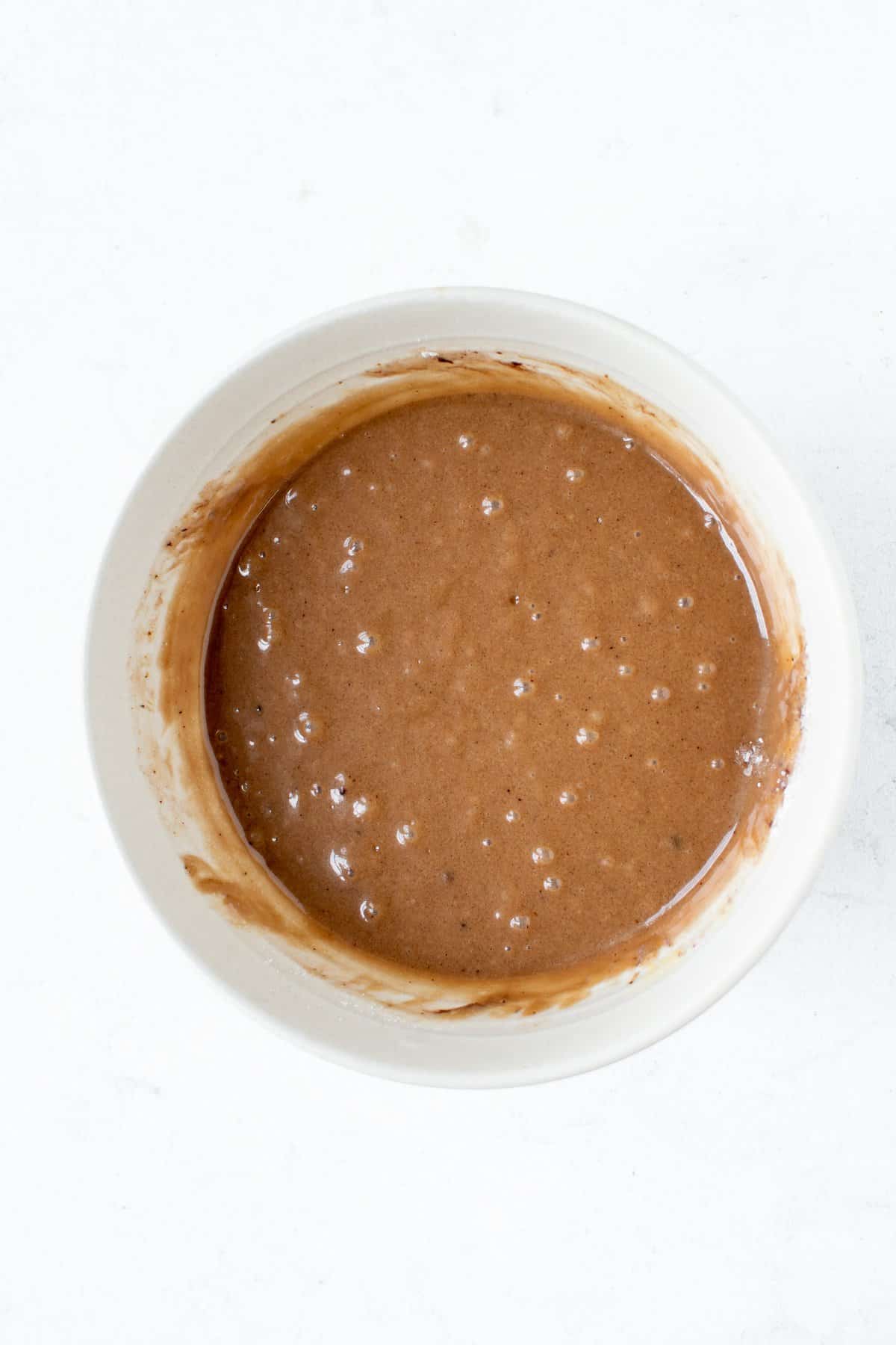 Chocolate cake batter in a large white bowl on white background. 