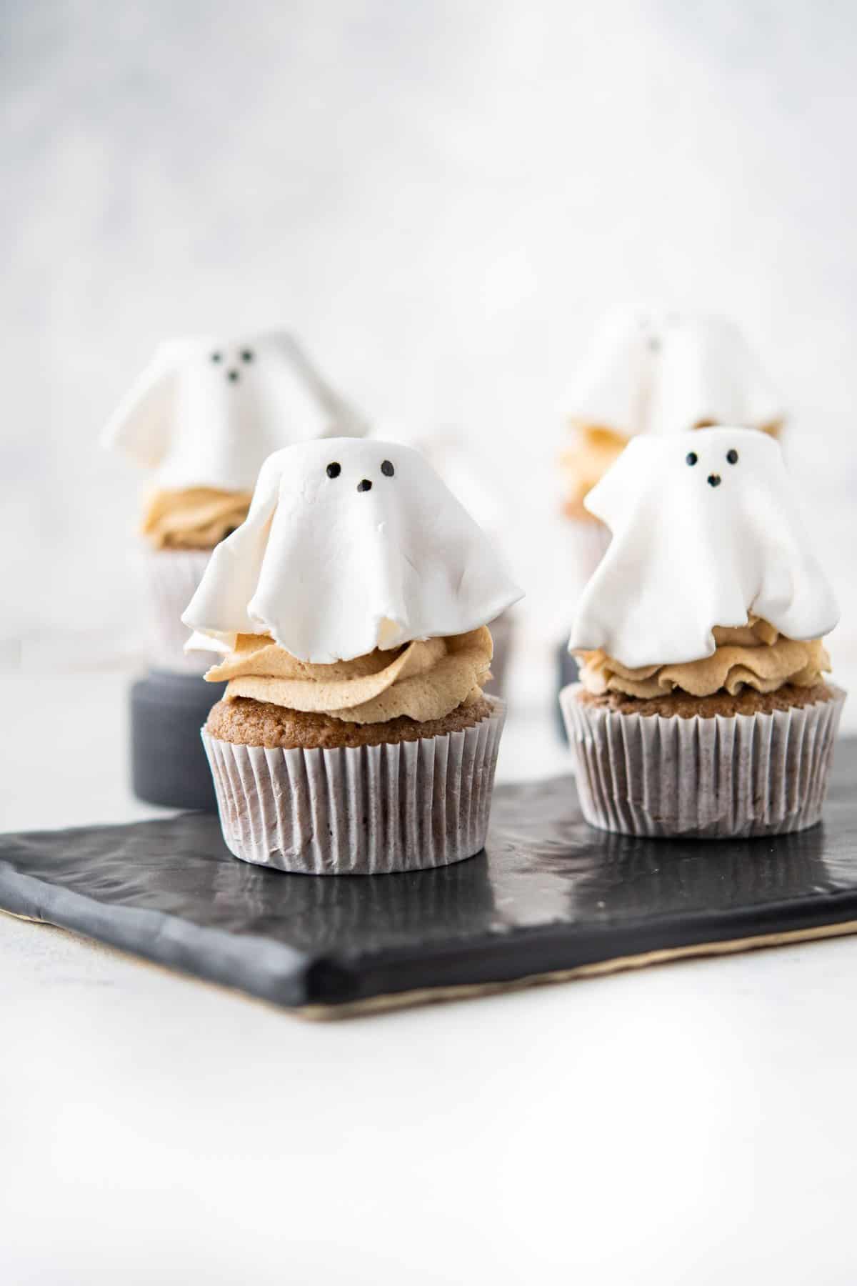 Ghost cupcakes on black rectangle plate and white background. 