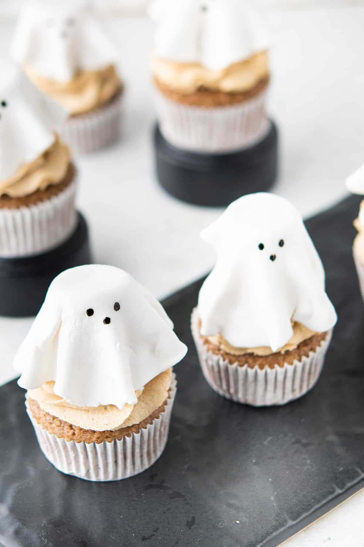 shot of the tops of the ghost cupcakes on a black rectangle dish. 