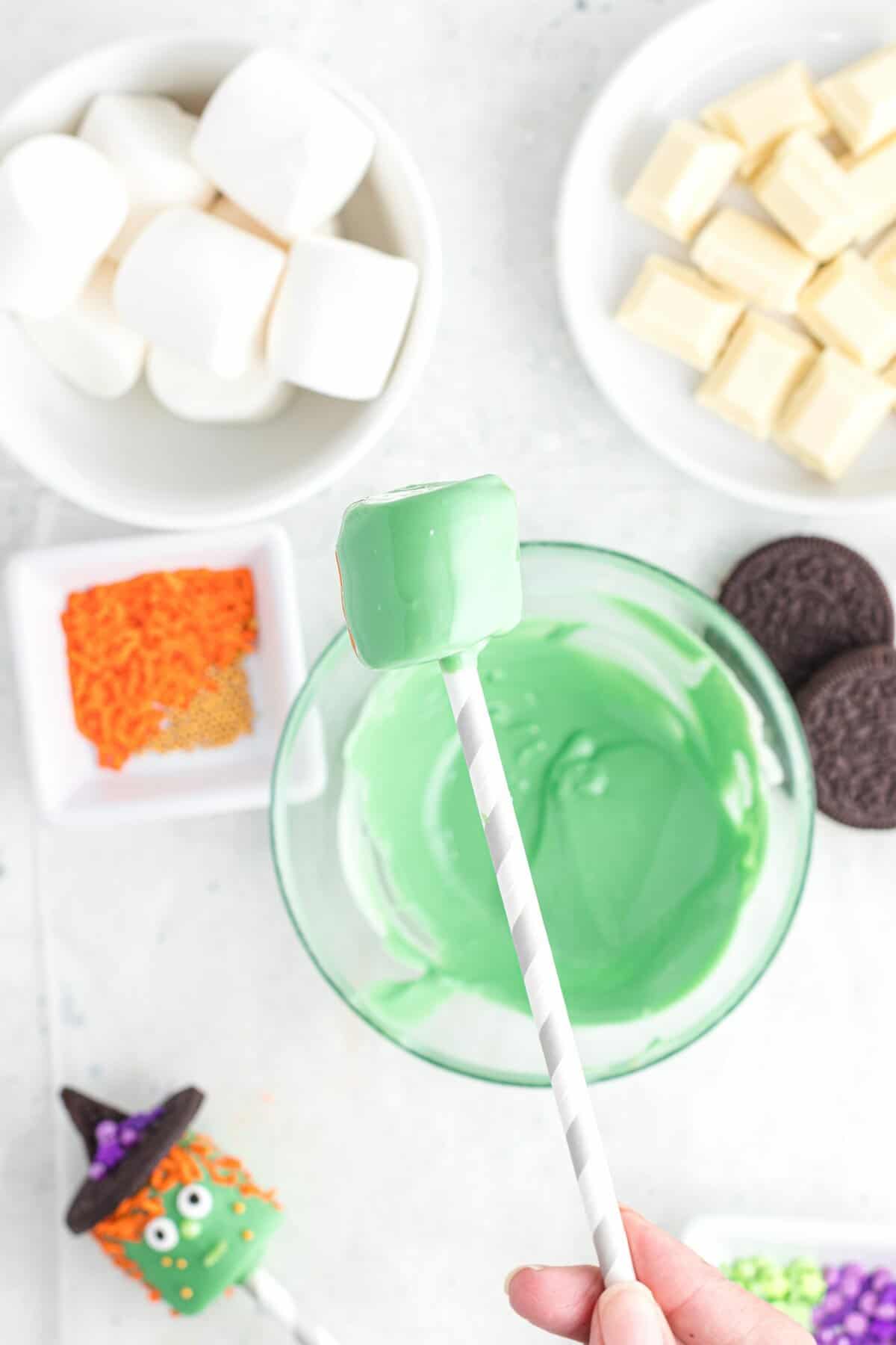 Dipping the marshmallow pop into the green melting chocolate bowl. 