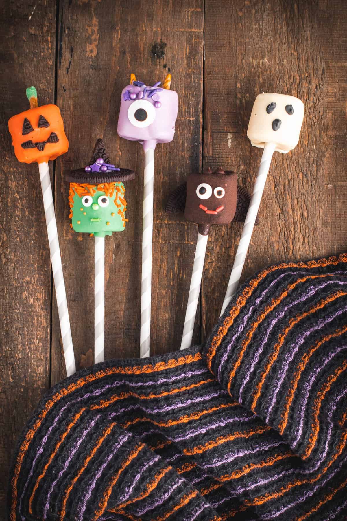 Overhead shot of the halloween dipped marshmallows on wooden background with black dishtowel. 