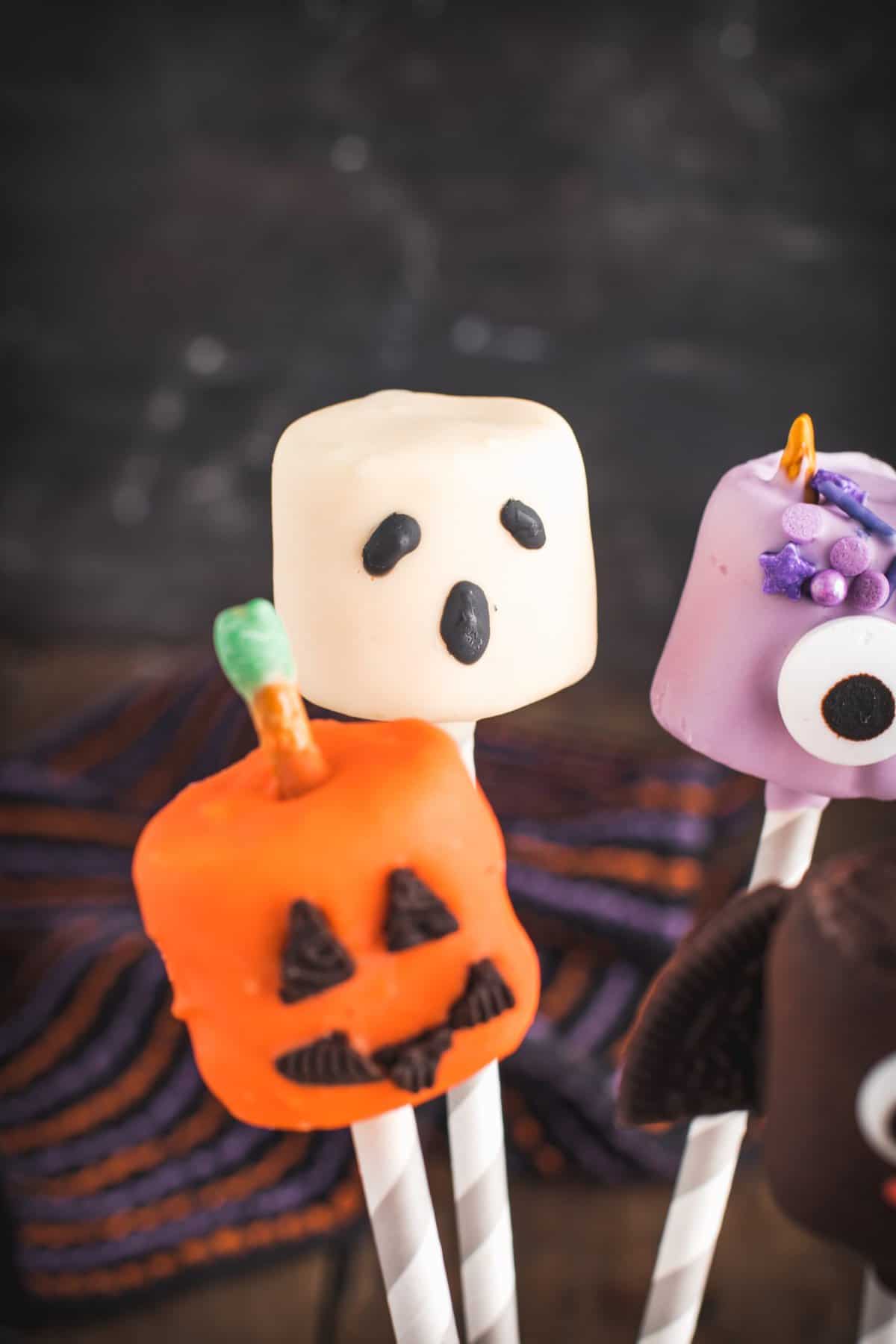 Ghost and jack-o-lantern pops set on paper straws, standing up. 