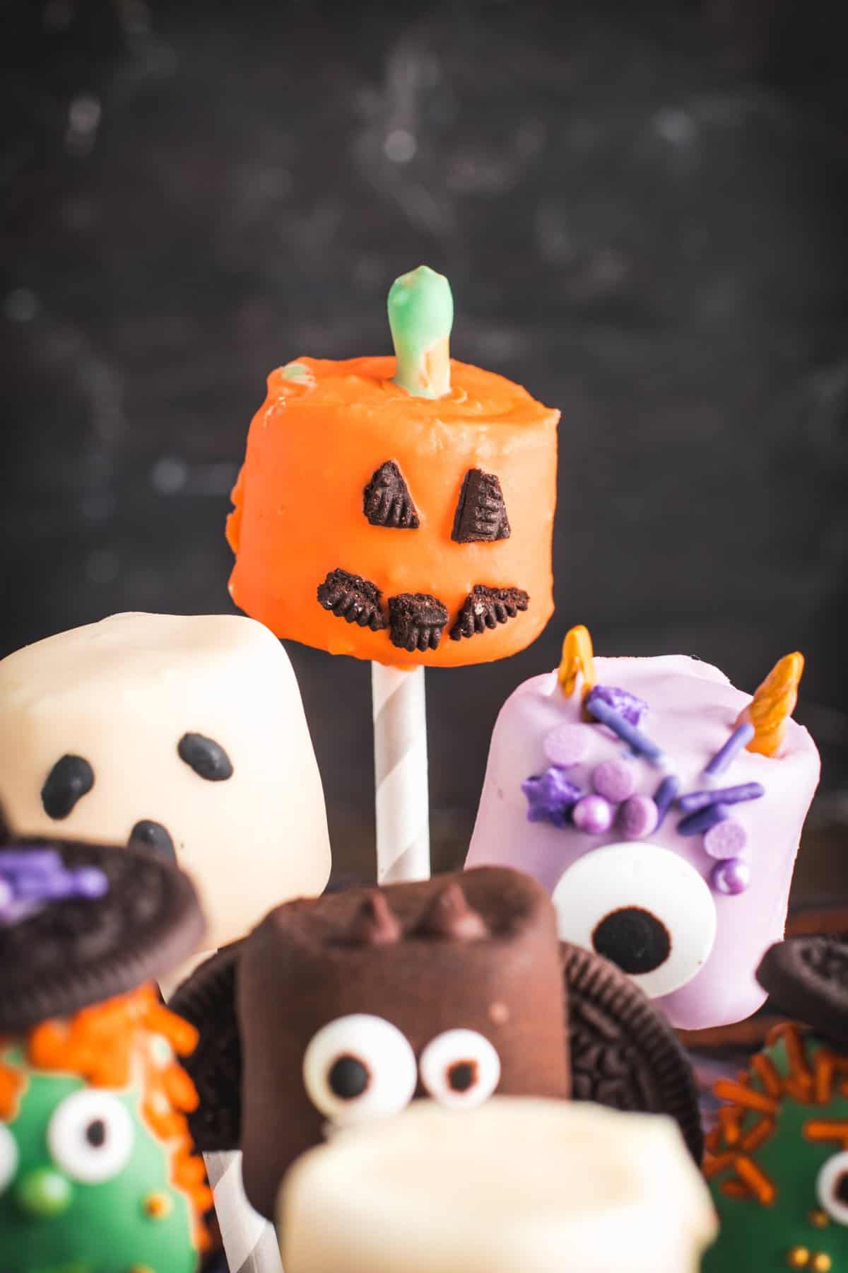 Jack-o-lantern cake pop focused in among the other pops. 