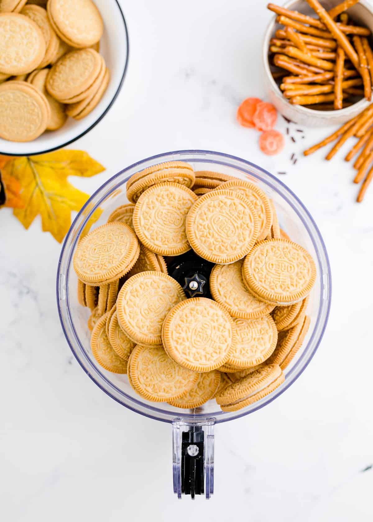 Adding the whole golden Oreos to the bowl of the food processor. 
