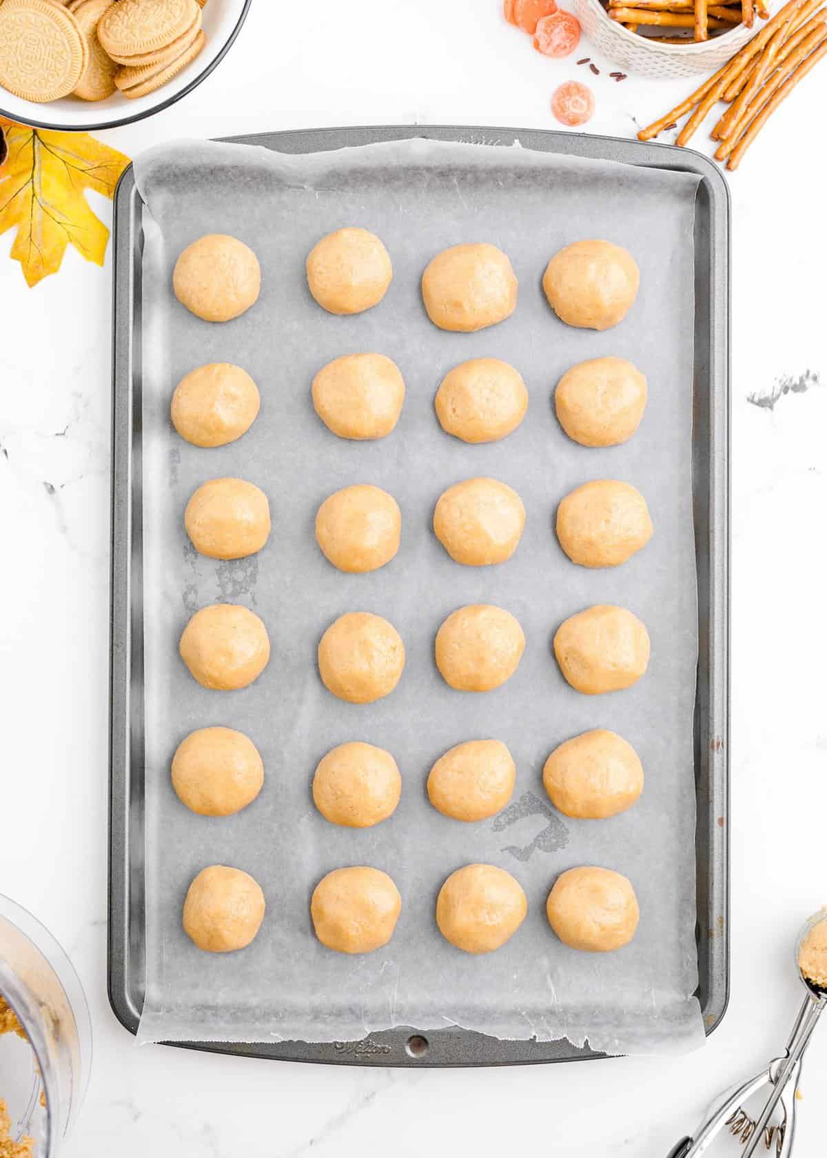 All of the rolled oreo pumpkin truffles on a wax paper lined cookie sheet. 