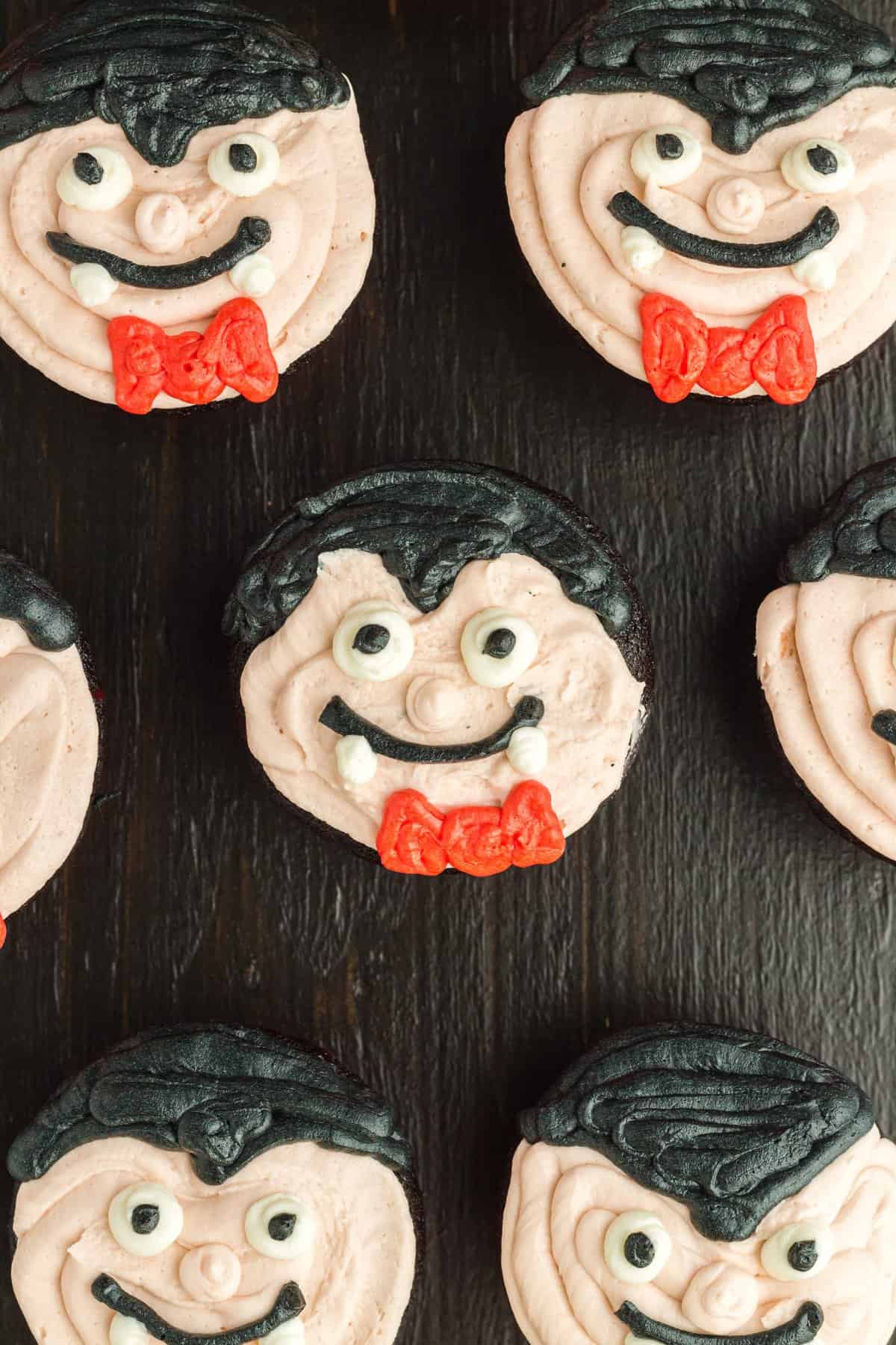 Overhead shot of the vampire face cupcakes on a black surface background.