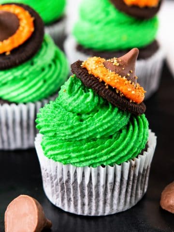 Square image of the witch's hat cupcakes on black plate.