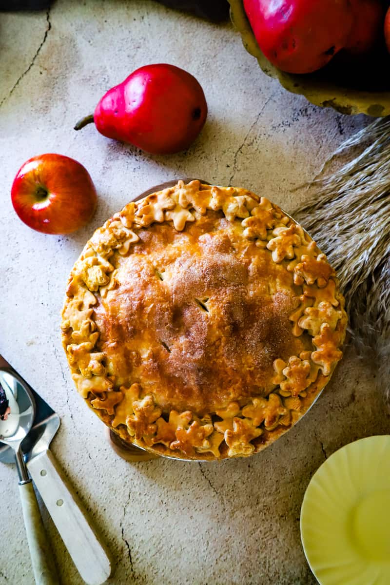 Overhead shot of the apple pear pie on beige background with fresh red pears. 