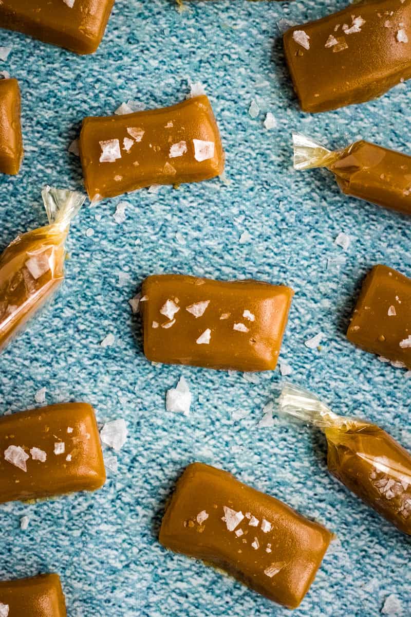 Overhead shot of the wrapped and unwrapped caramels on blue surface. 