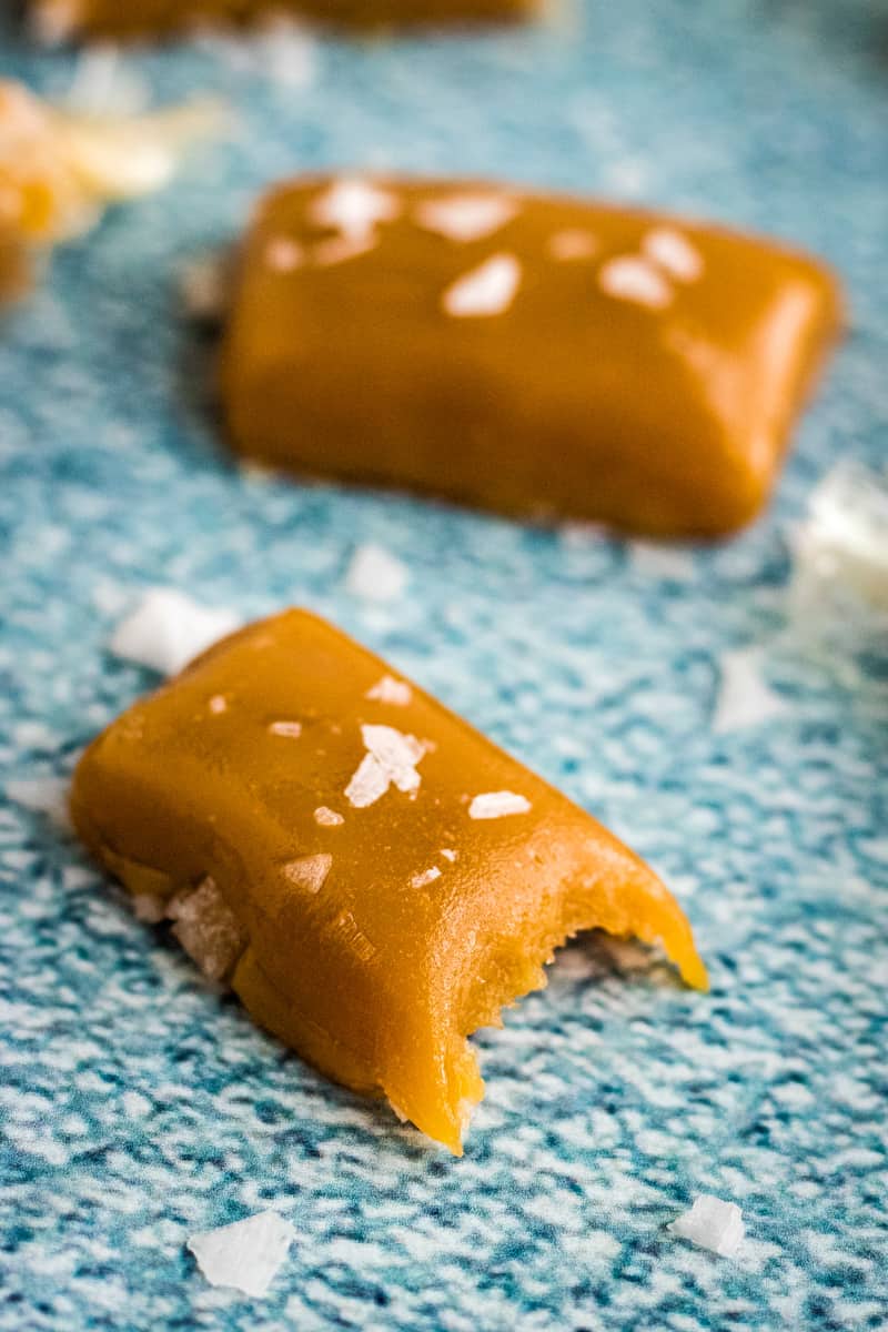 A brown sugar caramel square topped with sea salt and a bite taken out of it. 