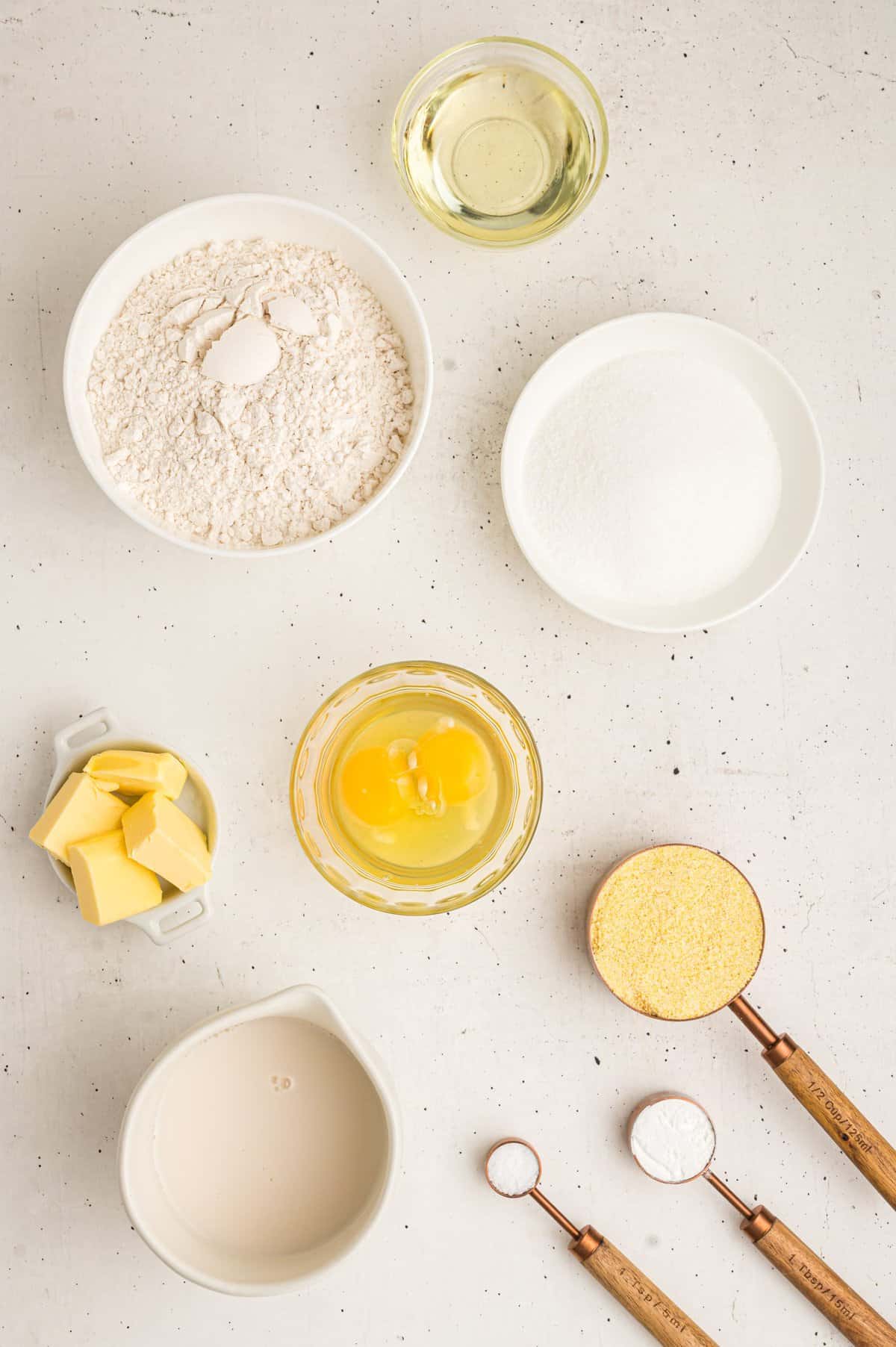 Ingredients to make the cornbread in small white bowls.