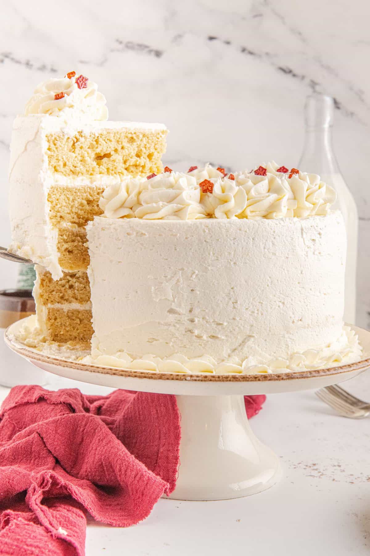 White maple three layer cake with cake knife taking a slice out. 