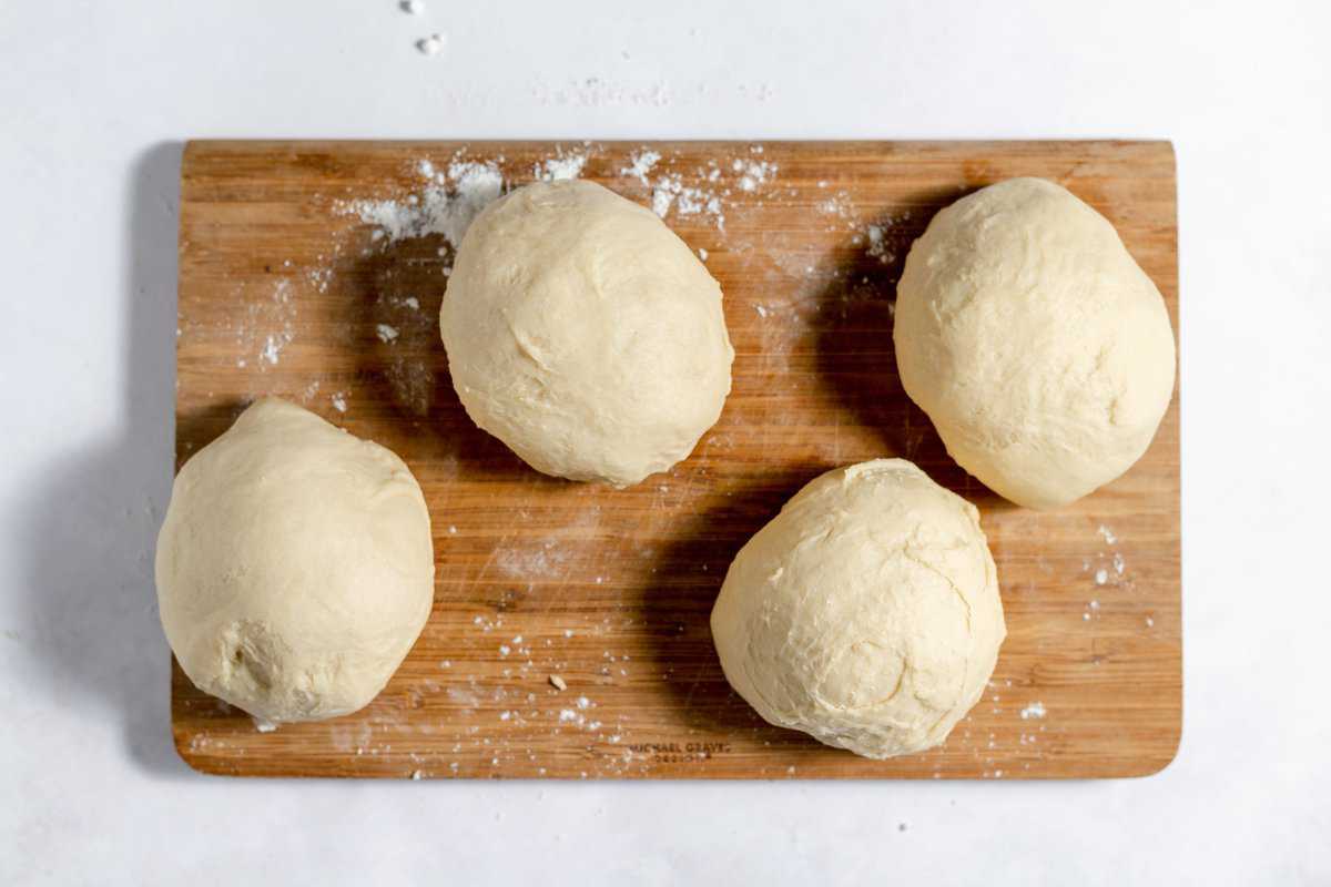 Divided dough into four small rounds on a wood cutting board. 