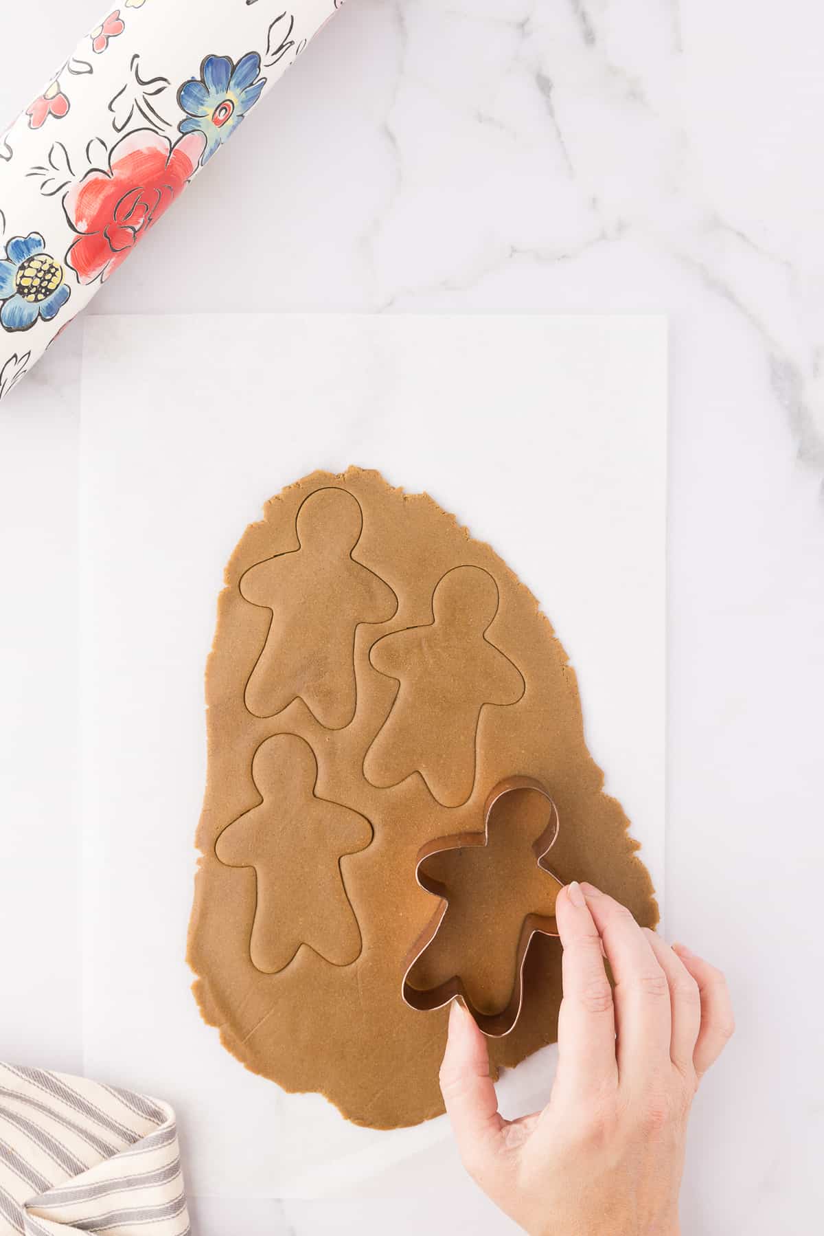 Cutting out gingerbread men with remaining dough on white background. 