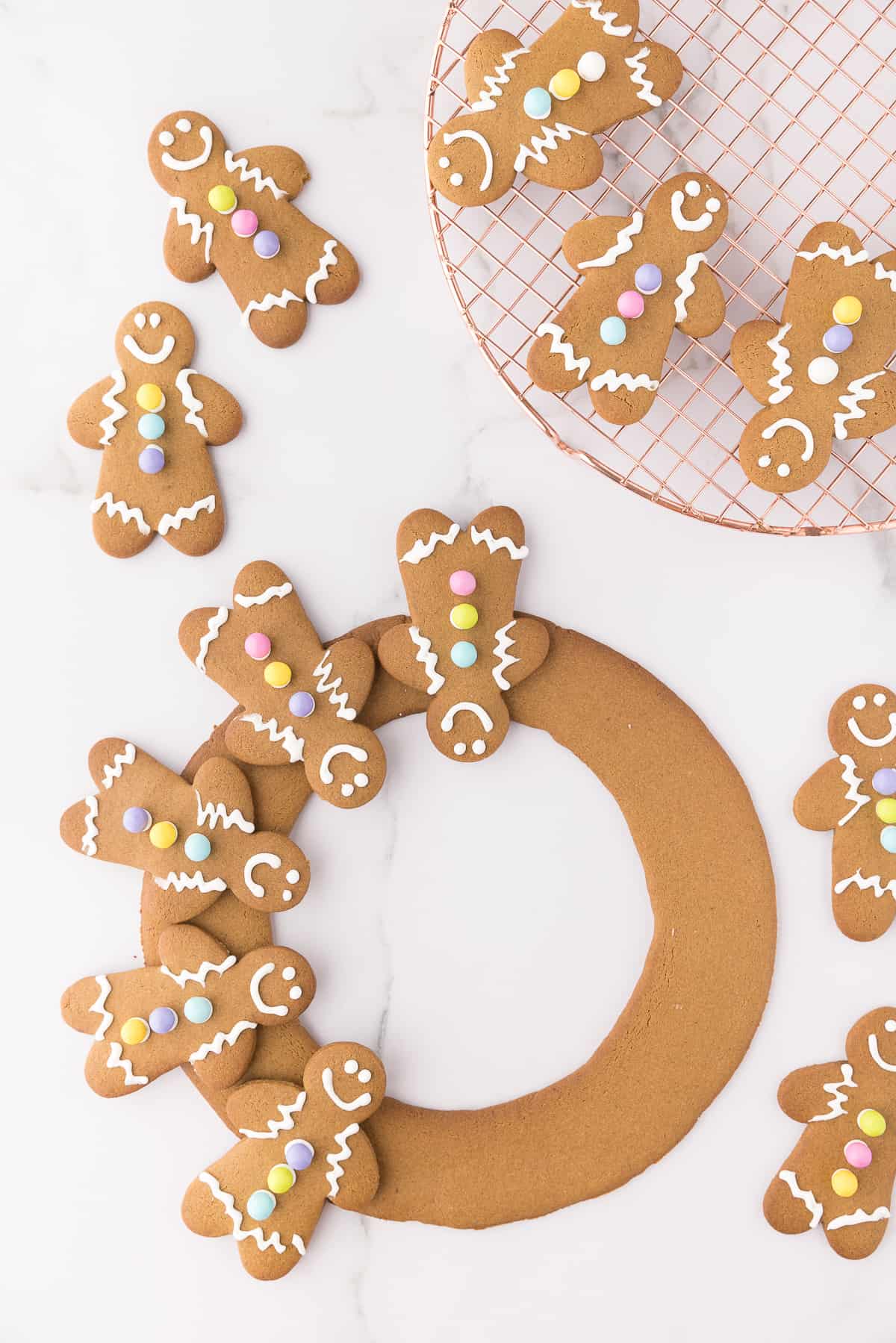 Assembling the gingerbread man wreath on white marble background. 