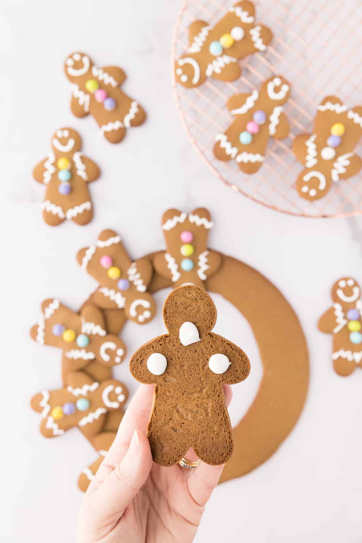 Adding dollops of royal icing to the back of the gingerbread man to secure on the wreath. 