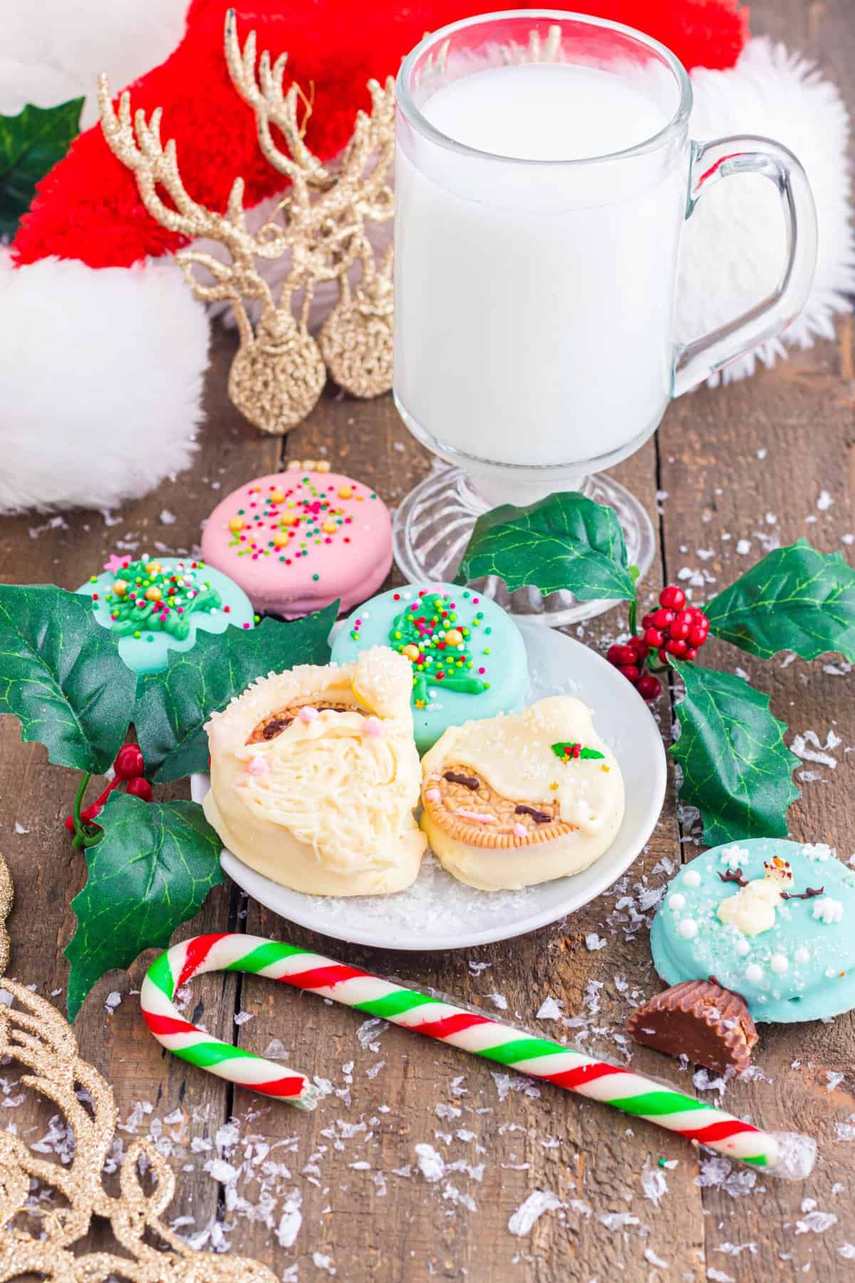 White plate with Christmas Oreos on wood background with cup of milk in background. 