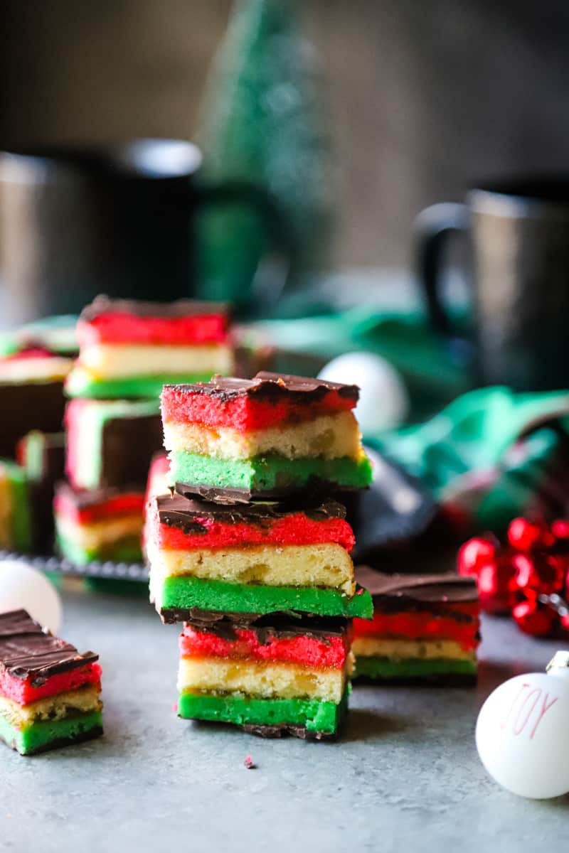 7-layer Italian cookies stacked with ornaments around them. 