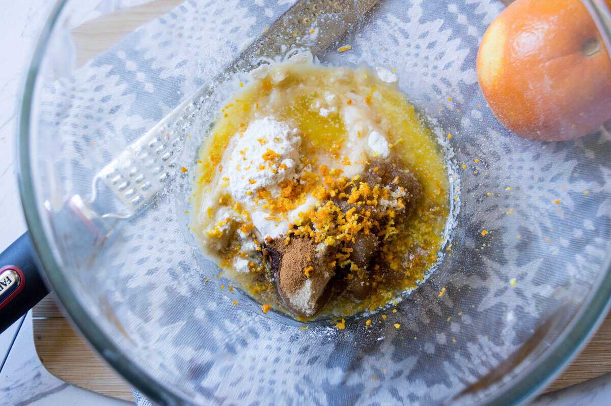 Glass bowl with sugar, butter, eggs, and orange zest to make the muffins. 