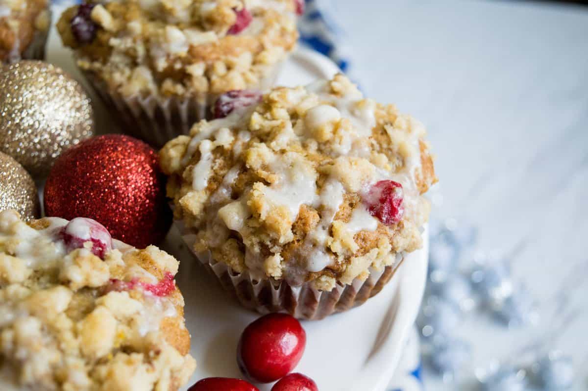 Muffins on white cake plate with red and gold ornaments around them. 