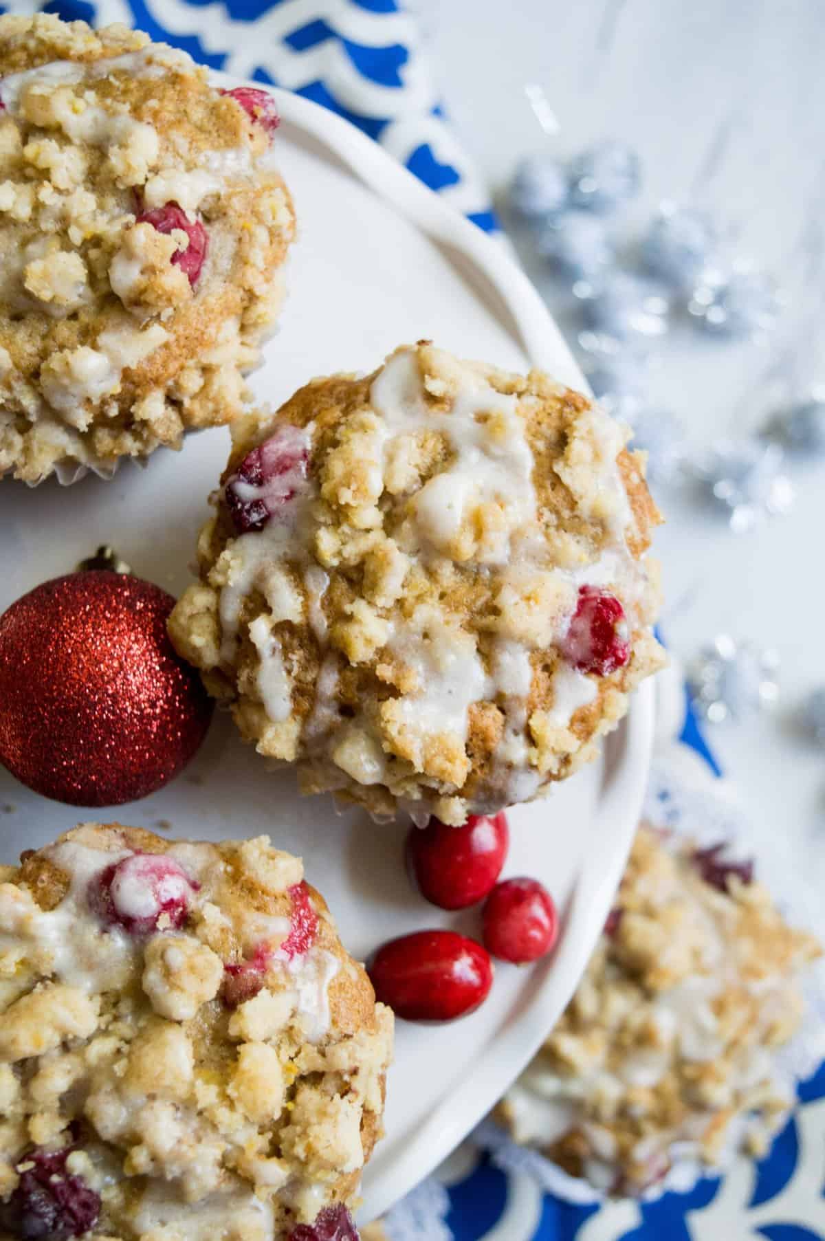 Overhead shot of the muffins on a white cake plate with fresh cranberries around them. 