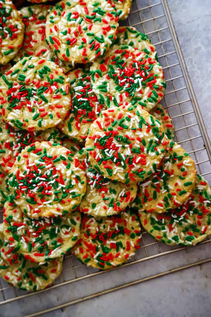 Stacked red and green sprinkled cookies on a metal cooling rack. 