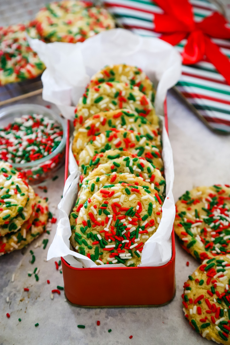 Cookies with red and green sprinkles in a red gift box tin.