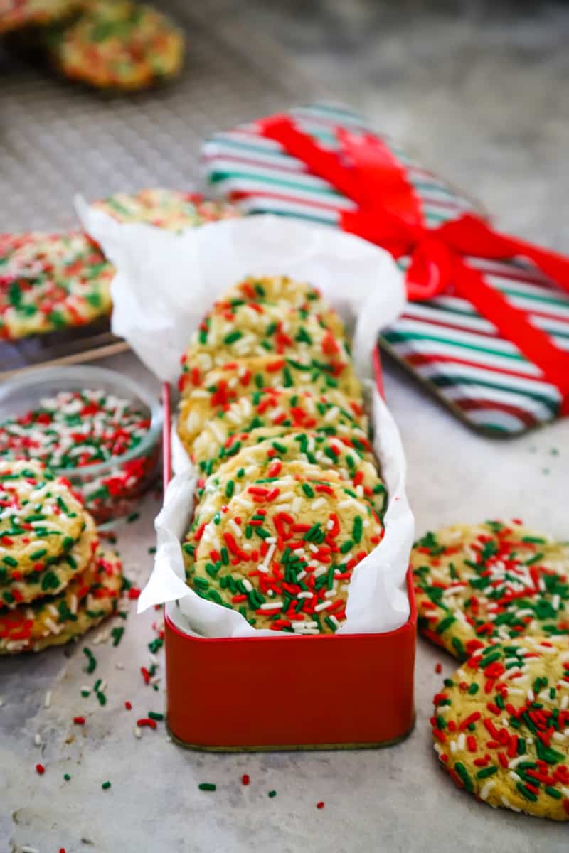 Cookies stacked in a long red tin lined with parchment paper. 