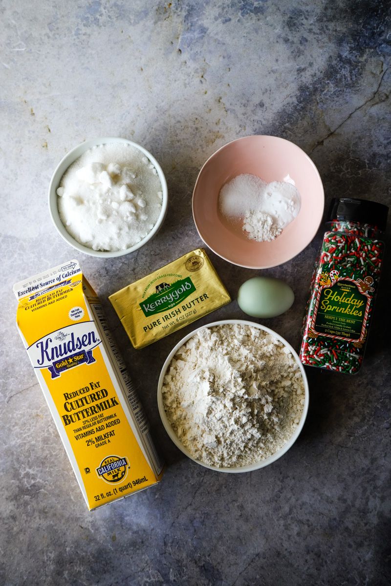 Ingredients to make the sugar cookies in small bowls on a metal background. 