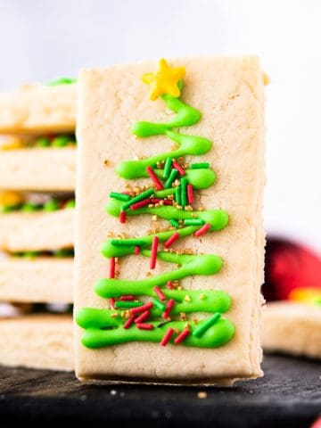 Rectangle shortbread cookie with a royal icing Christmas tree and sprinkles decoration.