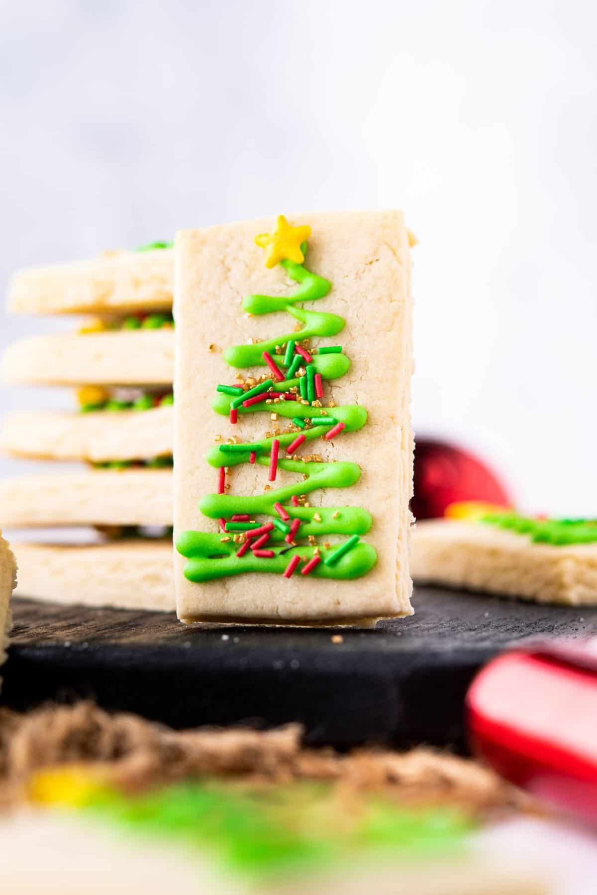 Shortbread cookies stacked with front one standing up to show the Christmas tree decoration on cookie. 