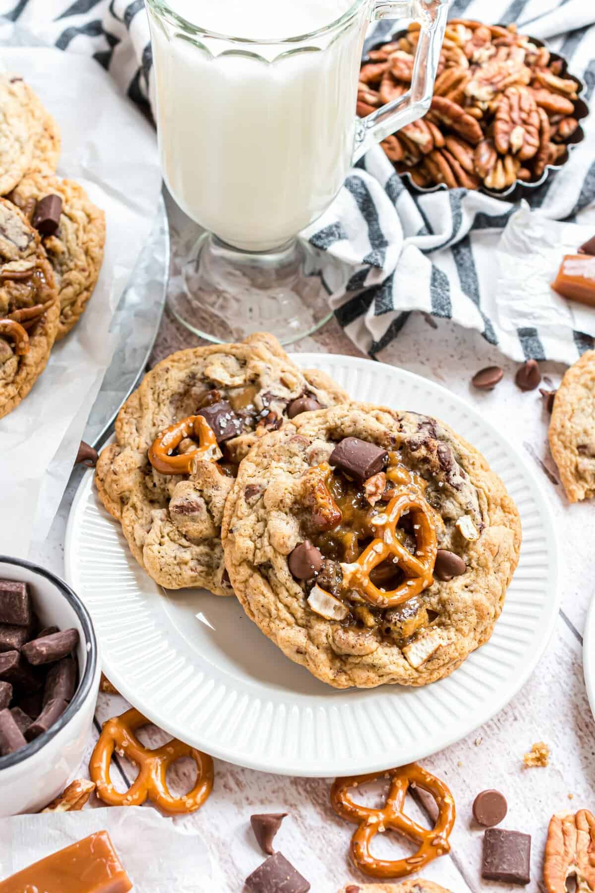 Two cookies on a white plate with a tall glass of milk in the background. 