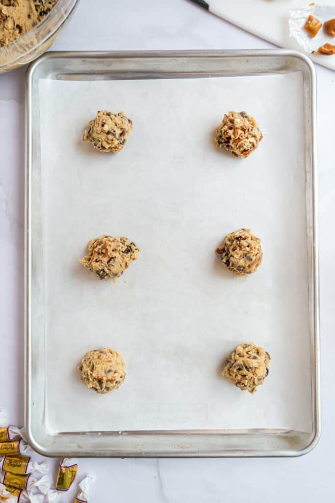 Overhead shots of a paper lined cookie sheets with six cookie dough balls. 