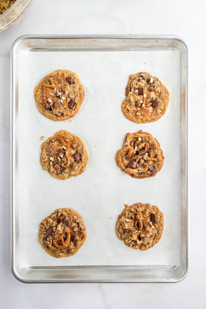 Baked cookies on a parchment lined cookie sheet on white background. 