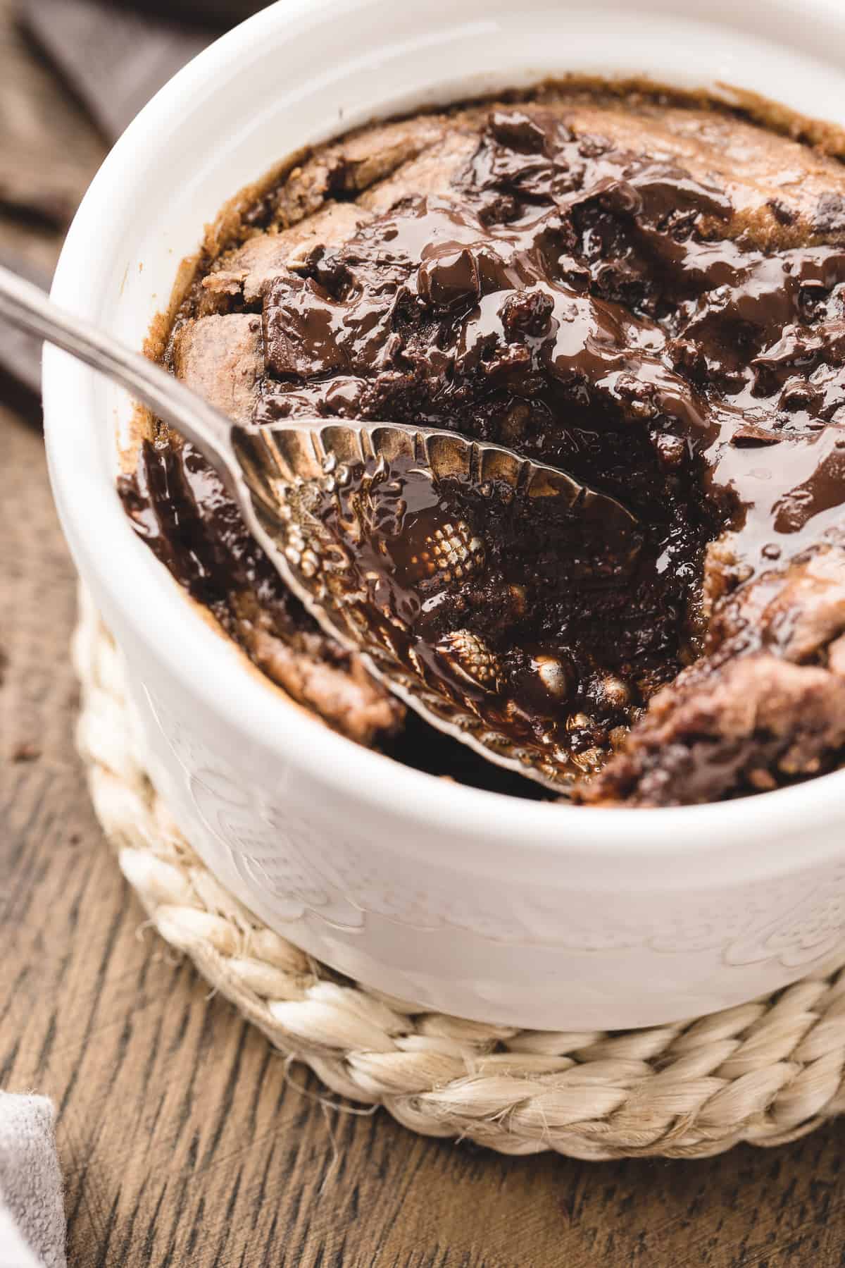 Up close photo of a spoon in the chocolate oats in white ramekin. 