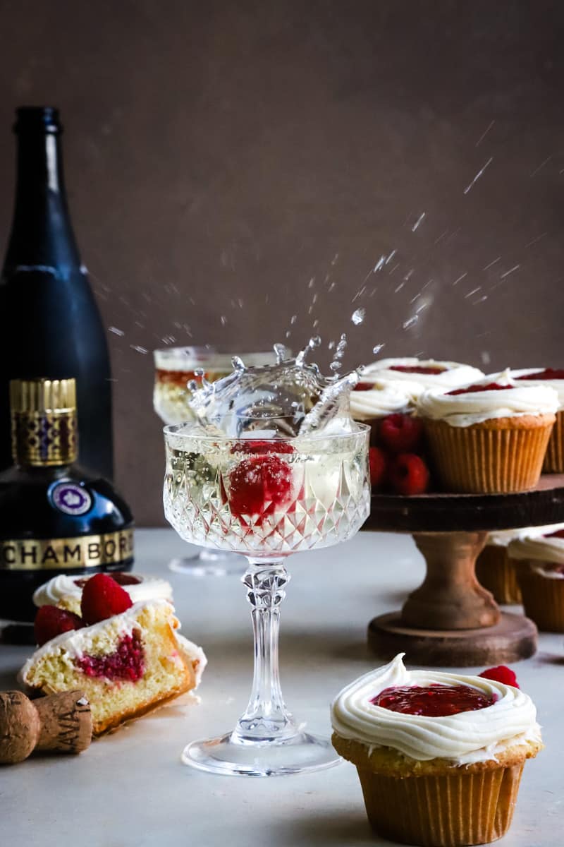 Raspberry being dropped into a glass of champagne causing a large splash. 