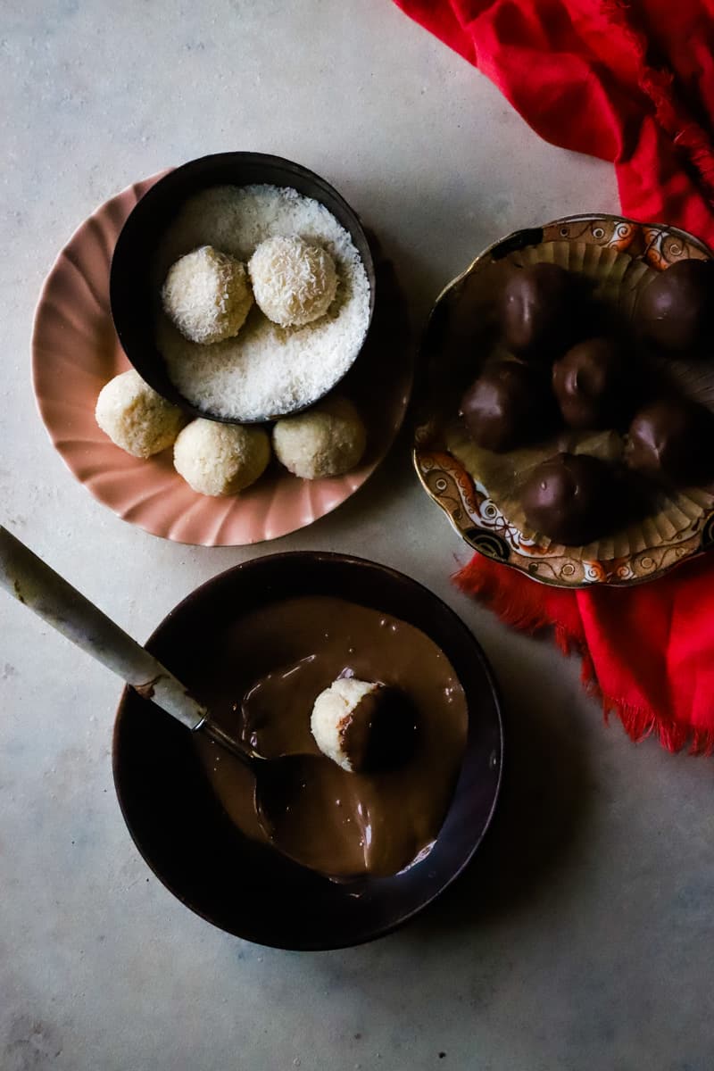 Overhead shot of balls being rolled in coconut and dipped in chocolate. 