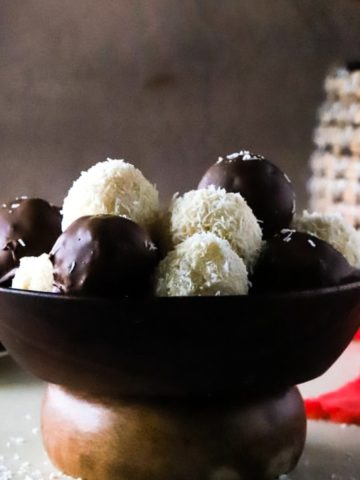Square feature image of coconut balls in a wooden bowl.