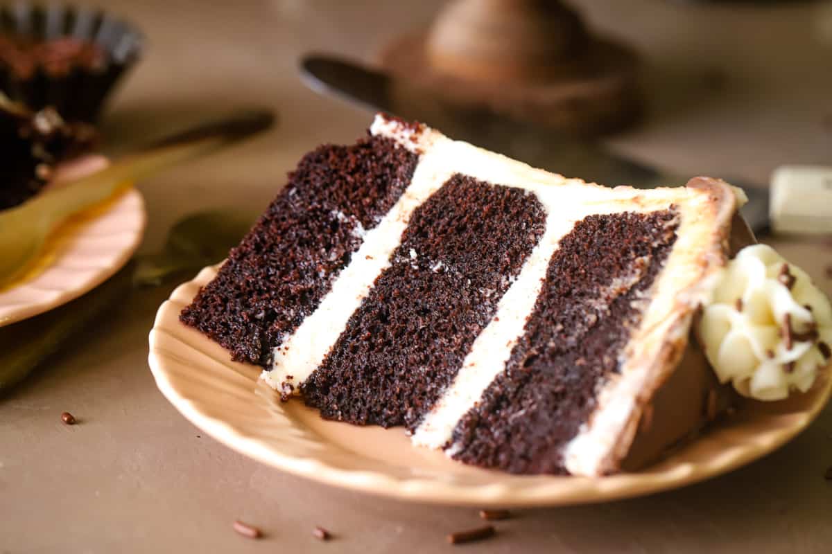 Up close shot of a chocolate baileys Irish cream 3 layer cake slice on pink plate. 