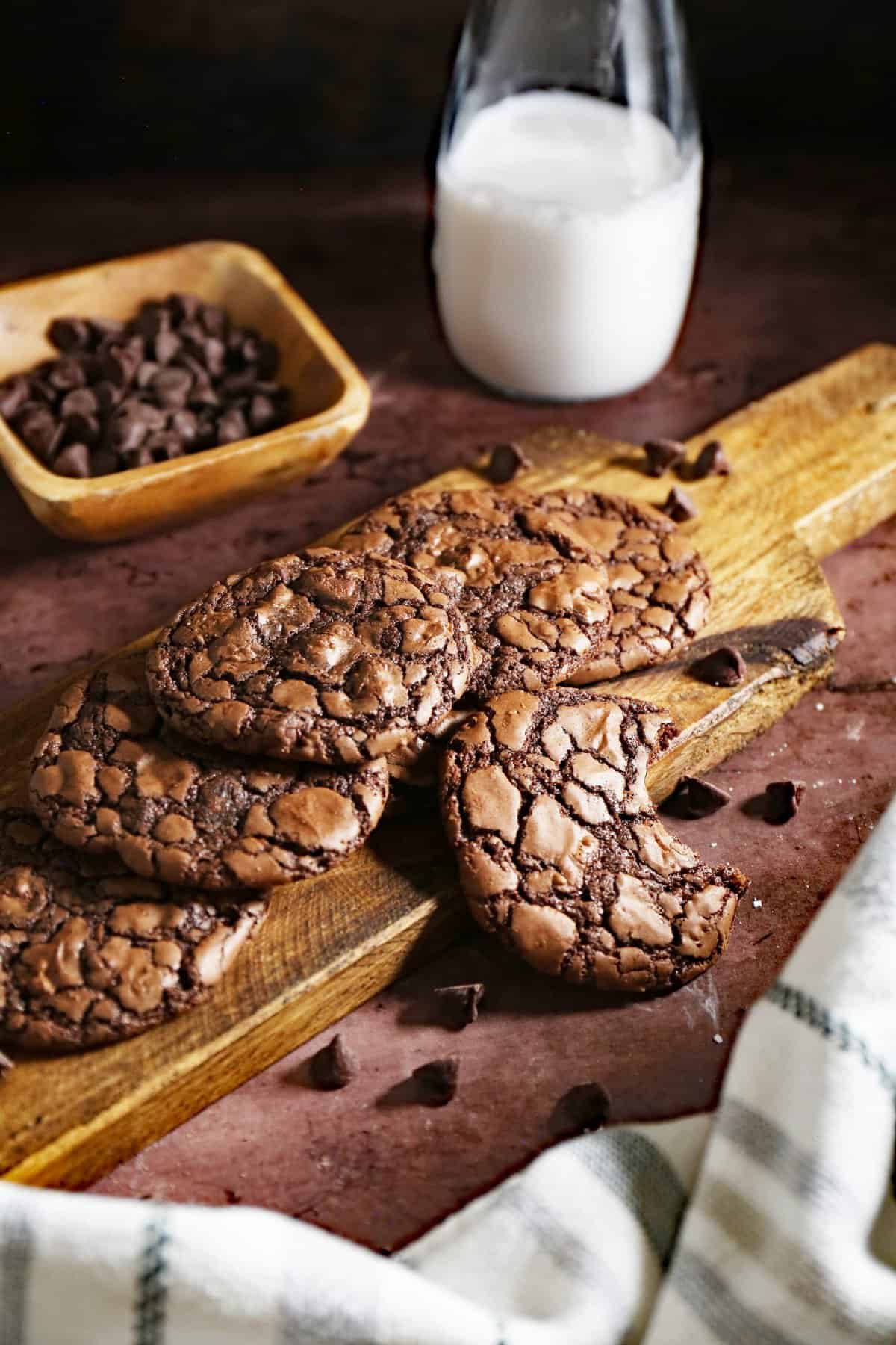 Cookies on a wood board with glass of milk in the background. 