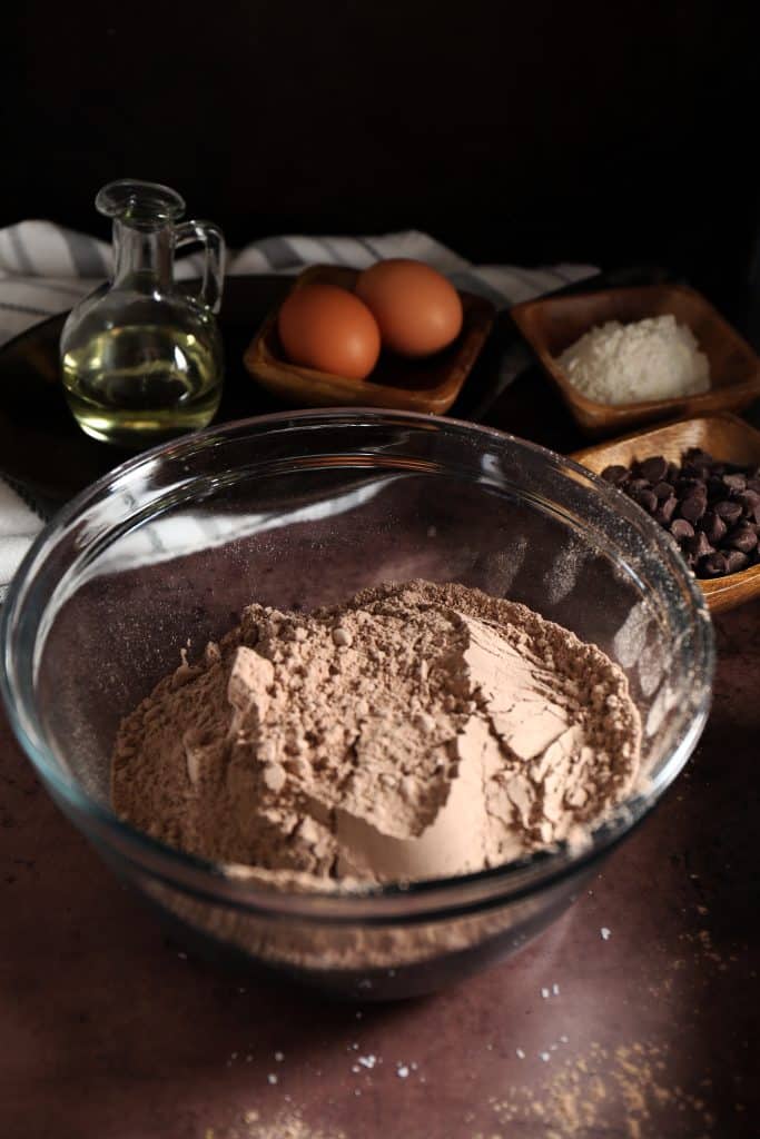 Brownie mix in large glass bowl with eggs in background. 