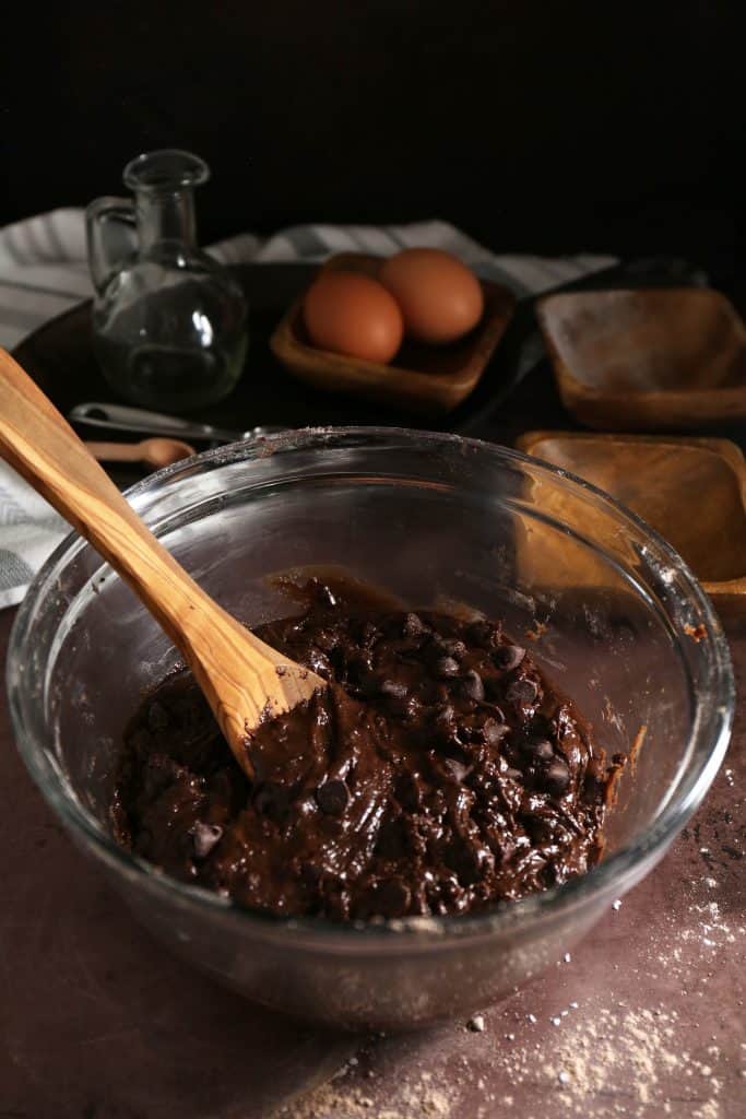 Wooden spoon stirring the chocolate chips into the dough. 