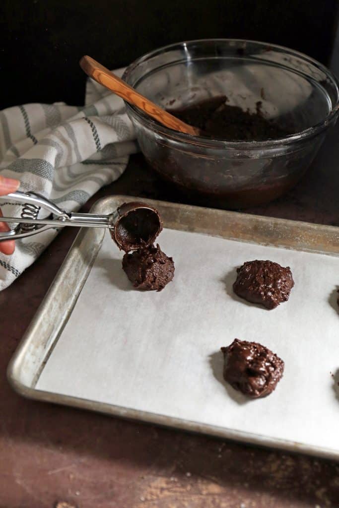 cookie scoop placing the dough balls on a lined cookie sheet. 