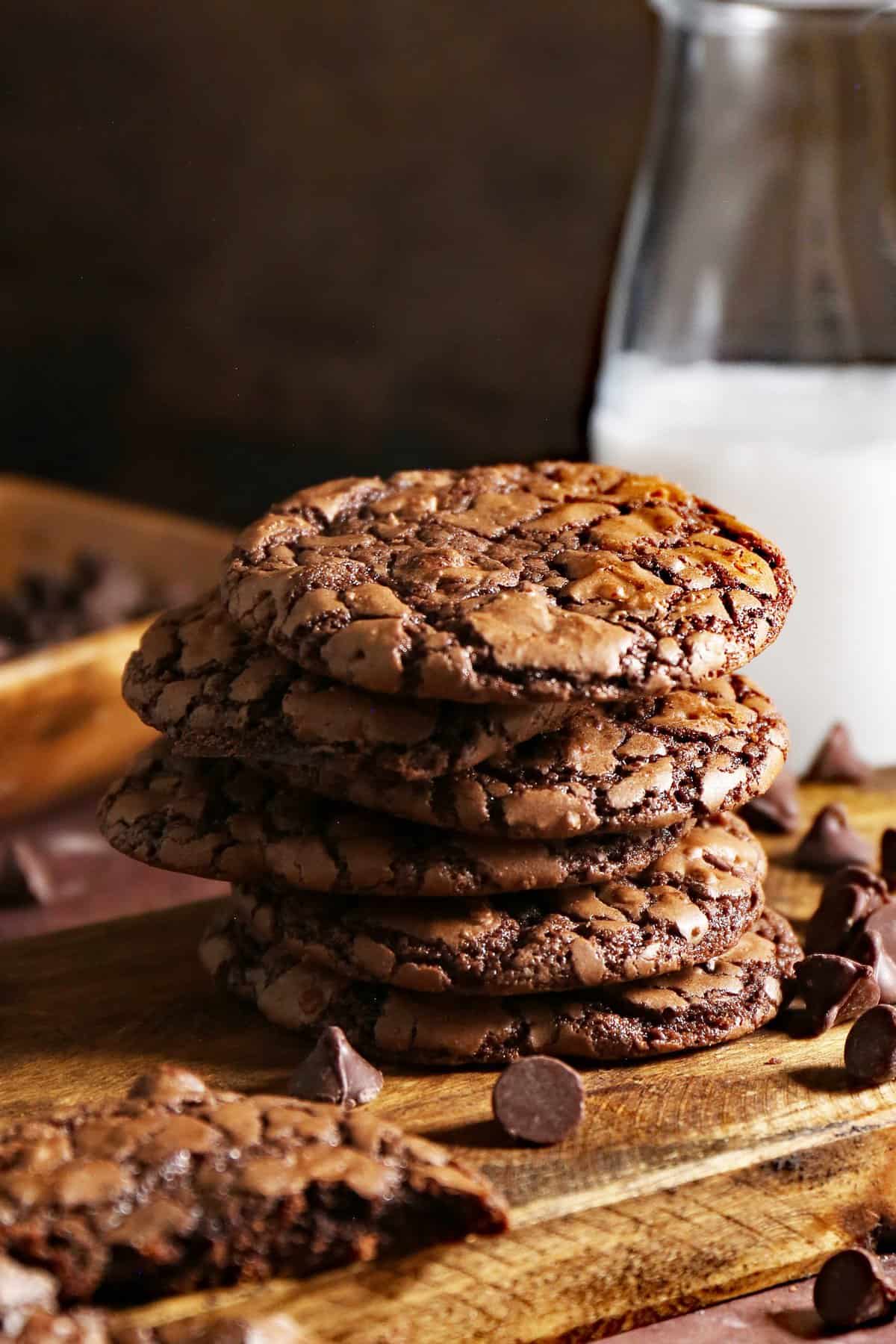 Stacked cookies on wood board with a glass of milk in background. 